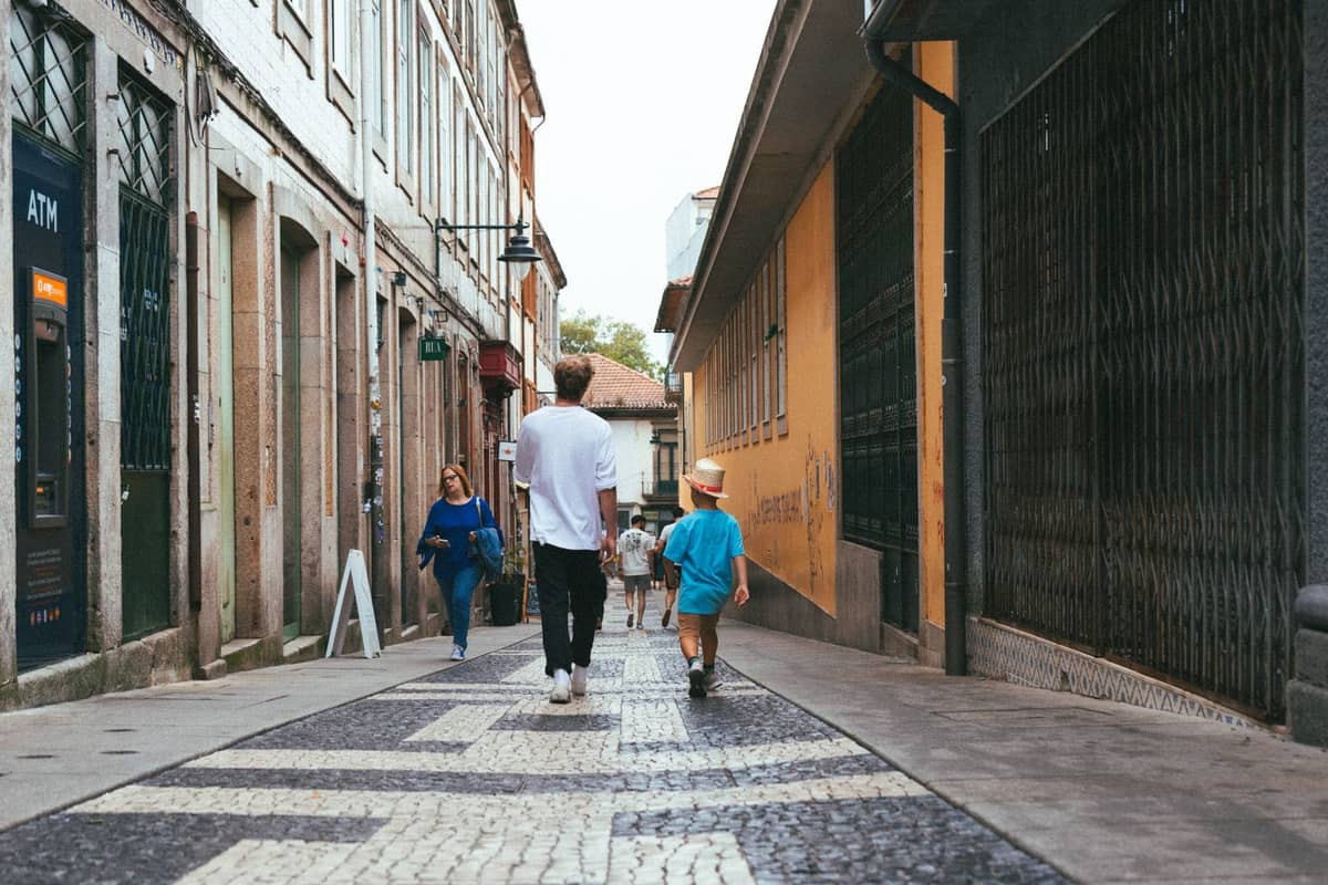 Ein Mann und ein Kind spazieren durch eine Fußgängerzone in Porto, gesäumt von traditionellen Gebäuden, und zeigen eine familienfreundliche städtische Umgebung.