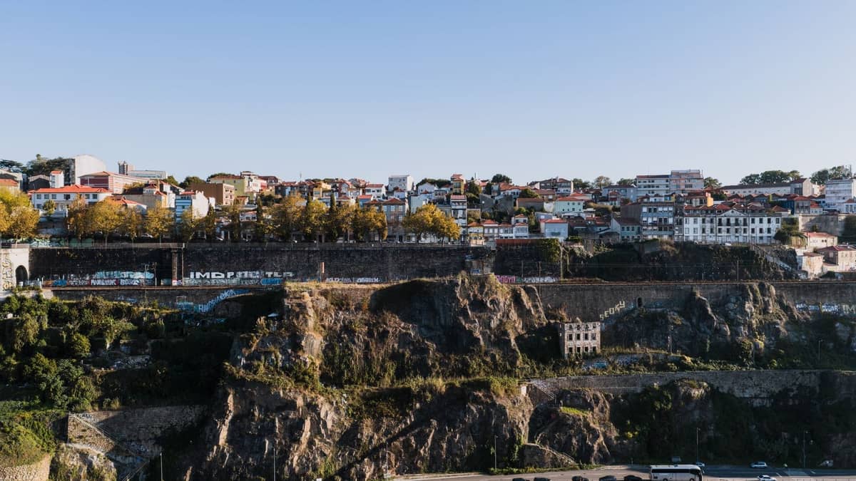 Weitblick über Porto mit steilen Felsenklippen unterhalb von Häuserreihen, der die dramatische Hanglage der Stadt hervorhebt.