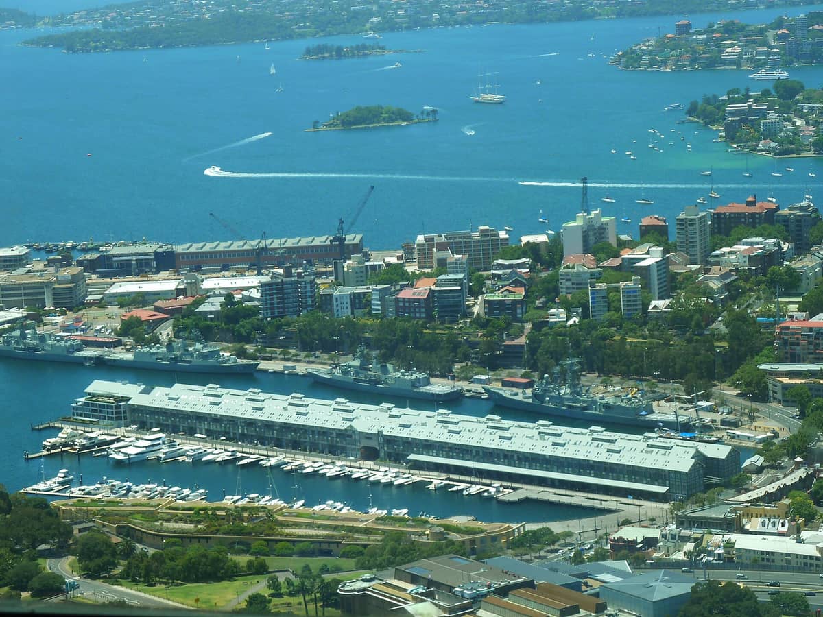 ภาพถ่ายมุมสูงของท่าเรือ Woolloomooloo Finger Wharf กับเรือยอทช์ บ้านเรือนริมอ่าว และฉากหลังเป็นอ่าวซิดนีย์สีฟ้า