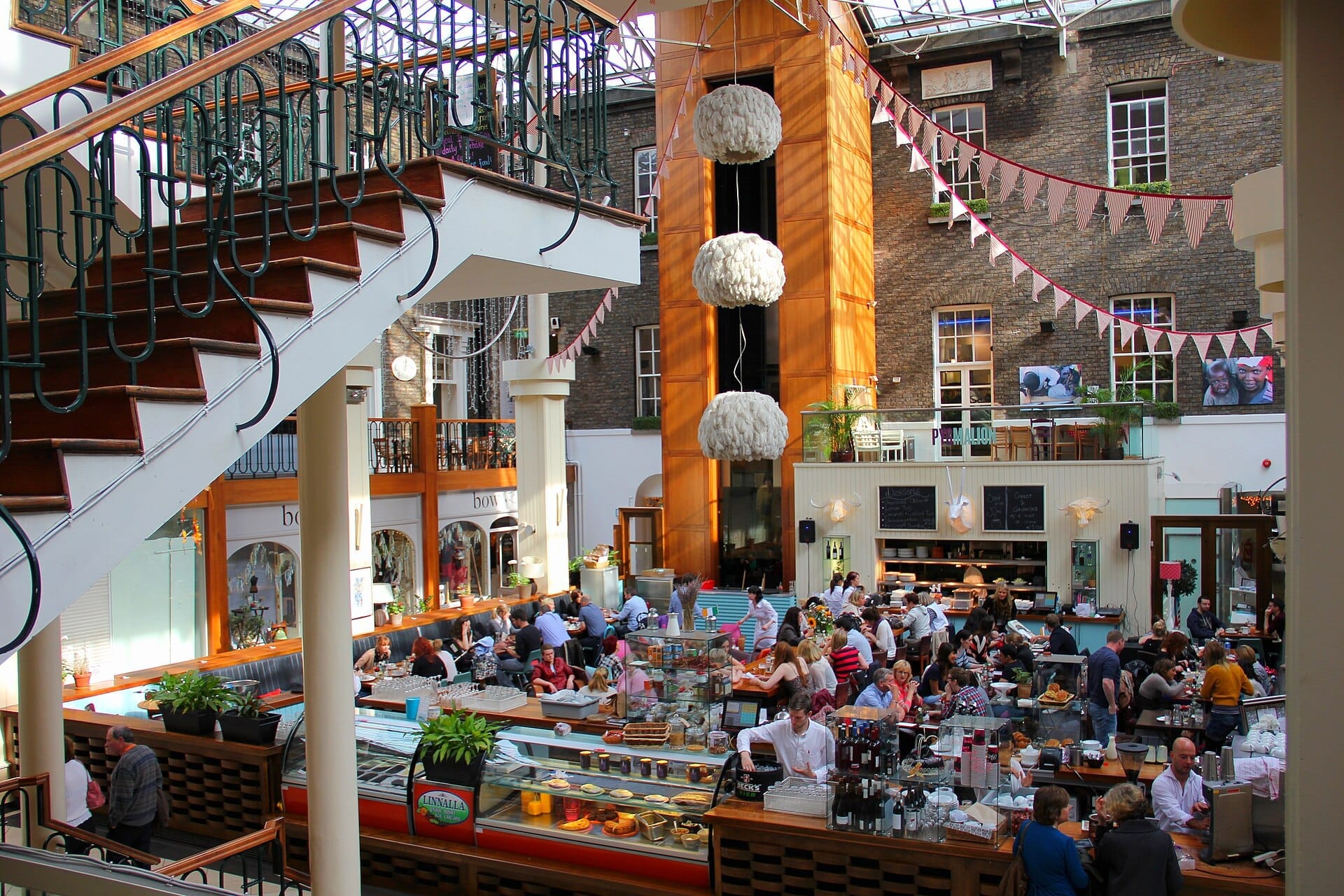 Il soleggiato cortile del Powerscourt Centre ospita un grande caffè affollato di visitatori, circondato da muri in mattoni in stile georgiano, bunting decorativi ed eleganti scale interne.