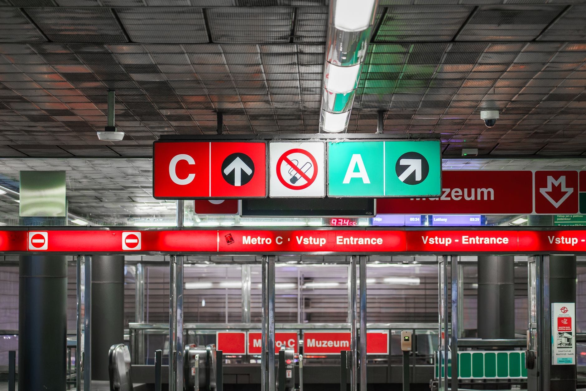 Eingang zur U-Bahn-Station Prague mit klaren Hinweisschildern für die Linien C und A, Fahrkartenschranken und Richtungspfeilen an der Decke.