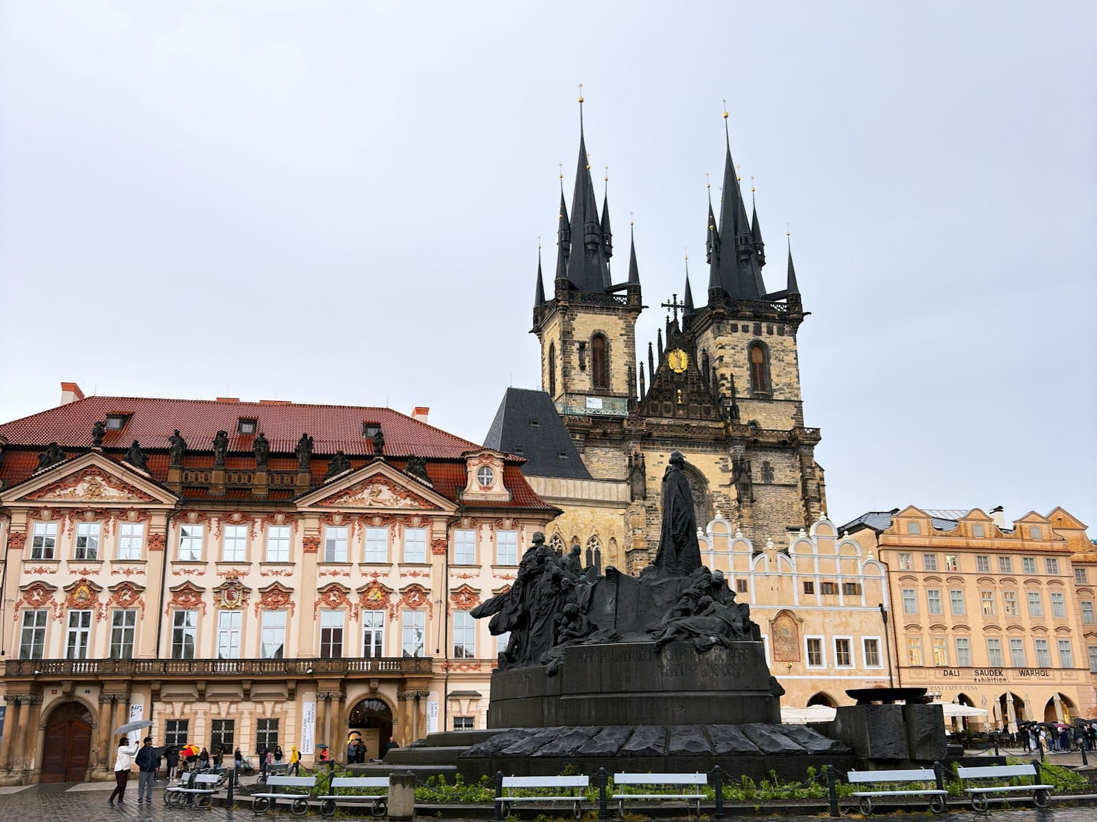 Memoriale di Jan Hus nella Piazza della Città Vecchia di Praga con la Chiesa di Týn e gli edifici storici sullo sfondo, fotografato in una giornata nuvolosa.