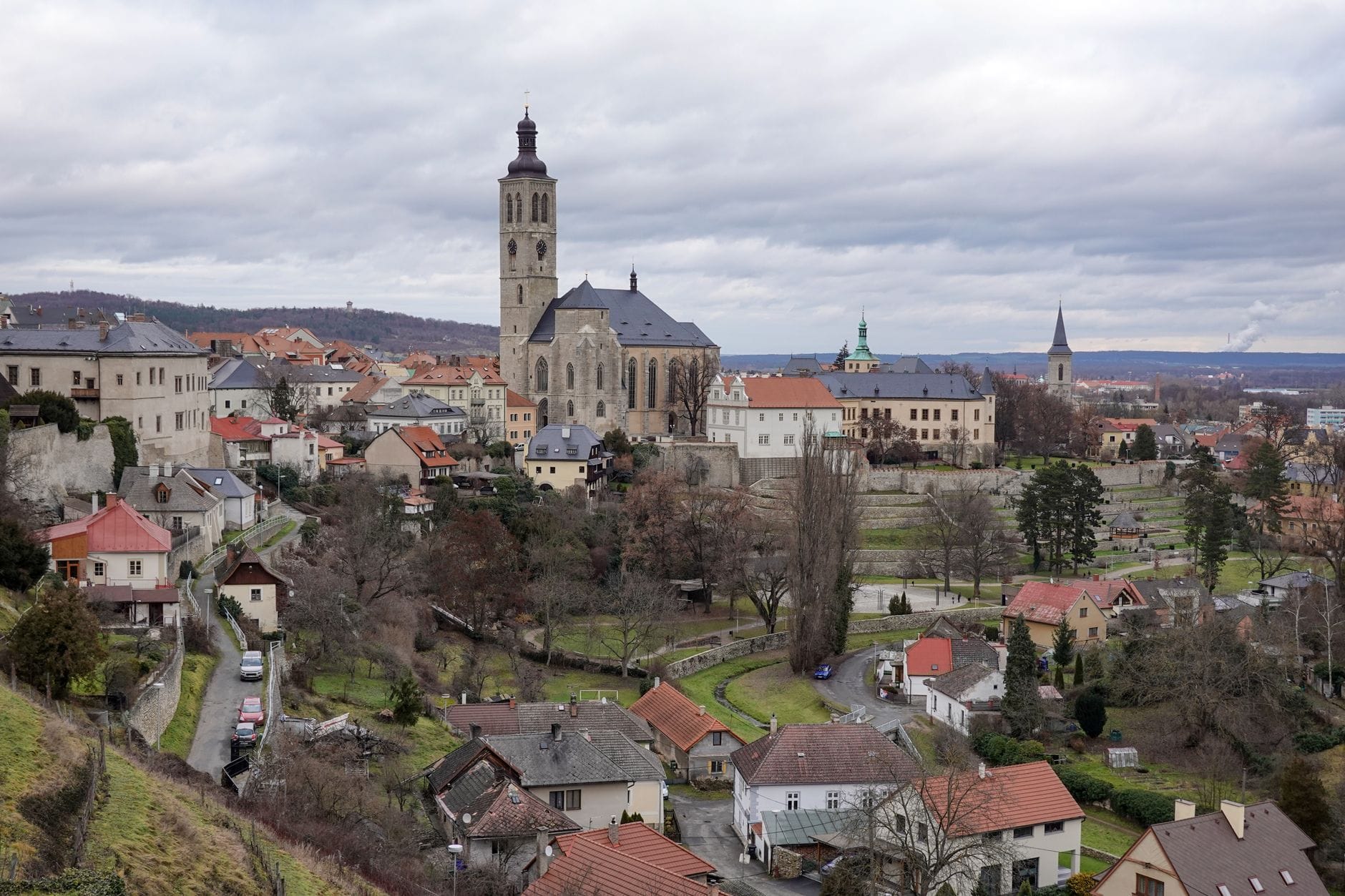 Weitläufige Ansicht der Stadt Kutná Hora mit dem St.-Barbara-Dom und den umliegenden Gebäuden an einem bewölkten Wintertag.