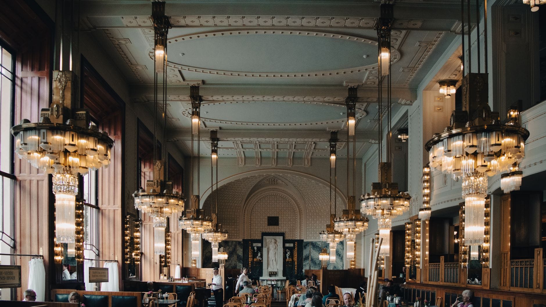 Großer, eleganter Speisesaal mit hohen Decken, prunkvollen Kronleuchtern und gut gekleideten Gästen an Tischen, wahrscheinlich ein historisches Gourmetrestaurant in Prag.