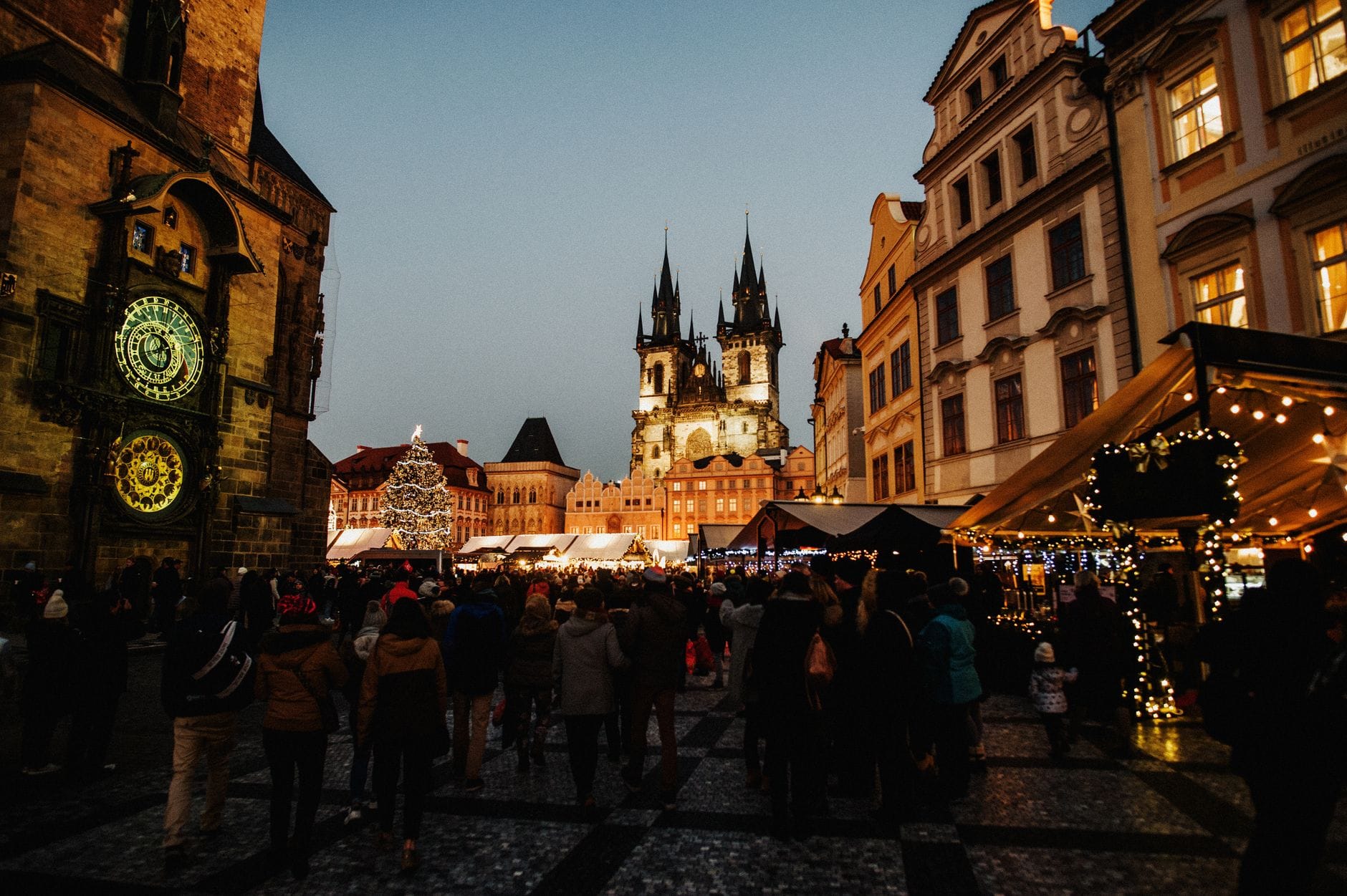 Nagtitipon ang mga tao sa Old Town Square ng Prague sa takipsilim, habang ang Astronomical Clock at Týn Church ay magandang naiilawan ng liwanag ng gabi.