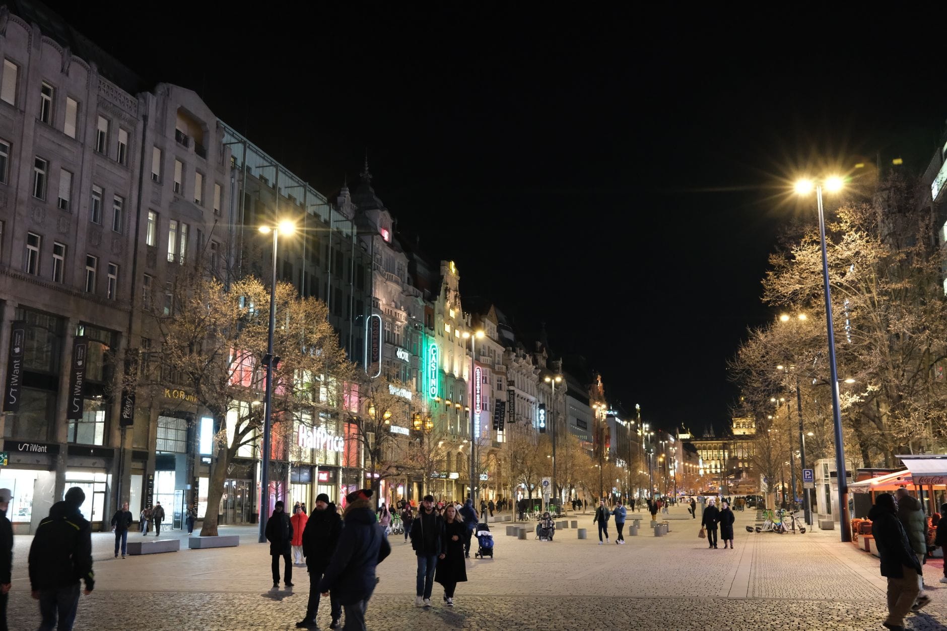 Malawak at masiglang tanawin ng Wenceslas Square sa gabi na may mga tao, mga naiilawang gusali, at isang maligayang kapaligiran sa lungsod sa Prague.