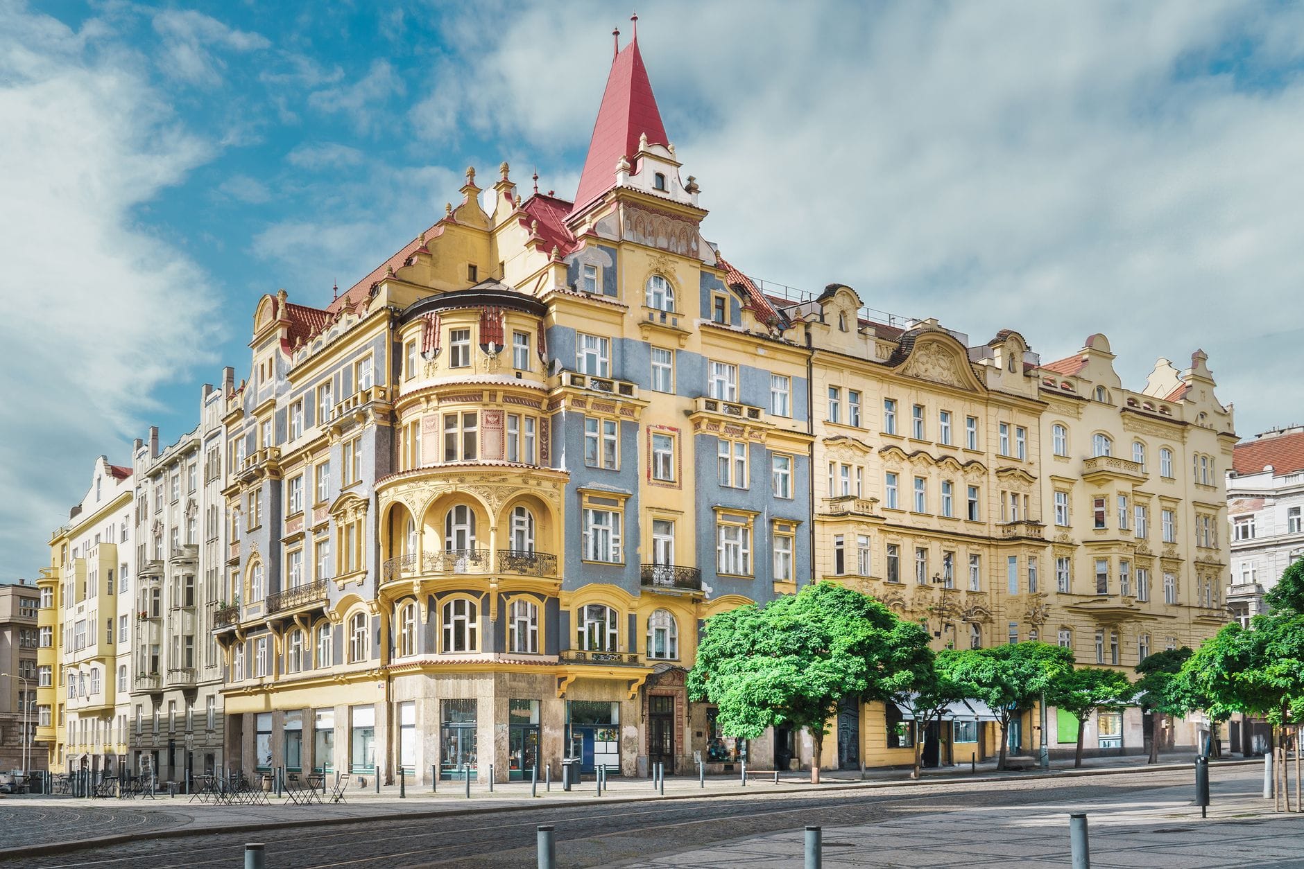 Elegante, farbenfrohe Jugendstilgebäude säumen eine breite Allee in Prag unter einem strahlend blauen Himmel und erinnern an exklusive Einkaufsstraßen wie die Pařížská.