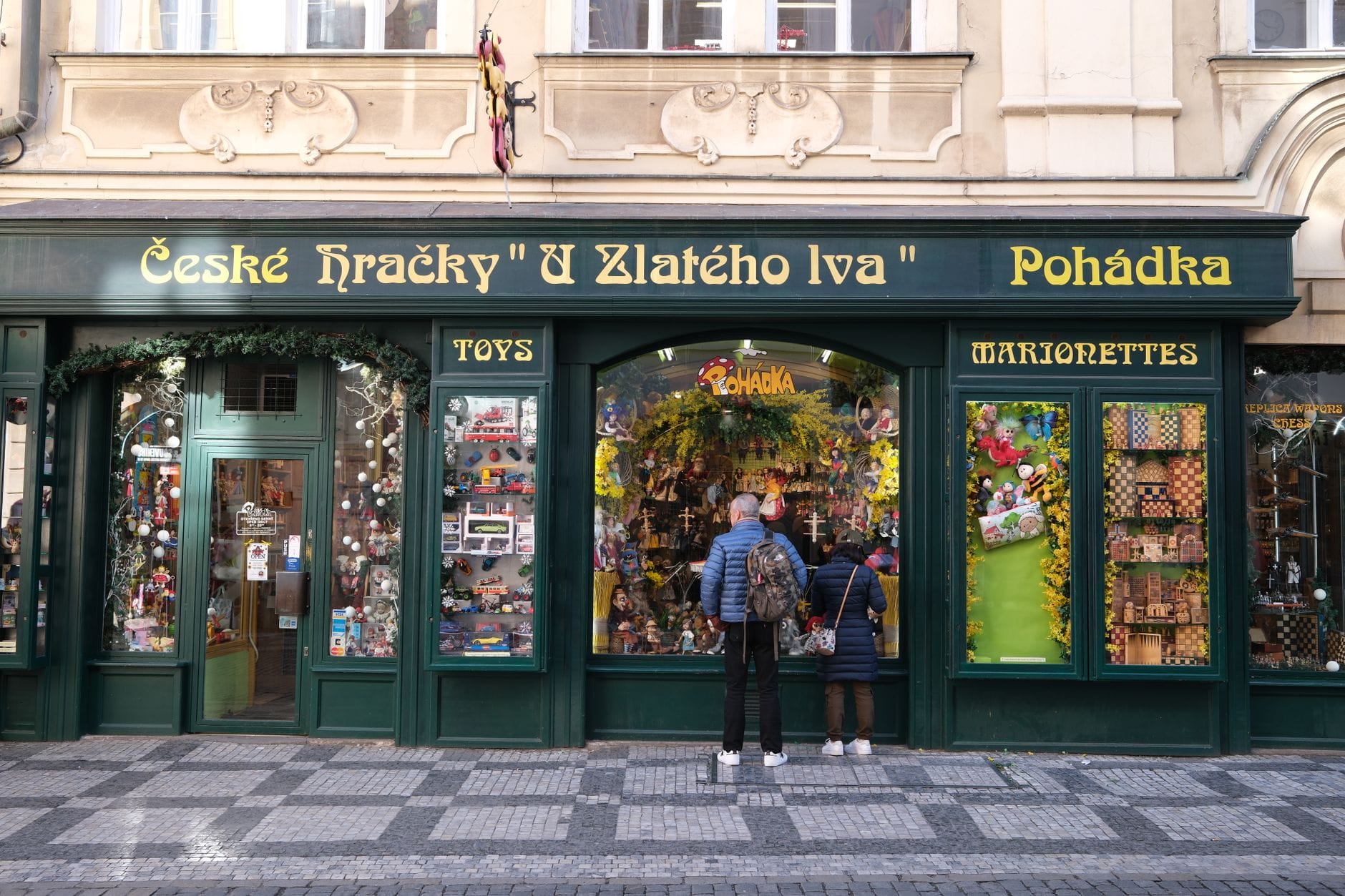 Traditionelle tschechische Spielzeug- und Marionettenladen-Fassade in Prag mit zwei Personen, die bunte Schaufenster betrachten.