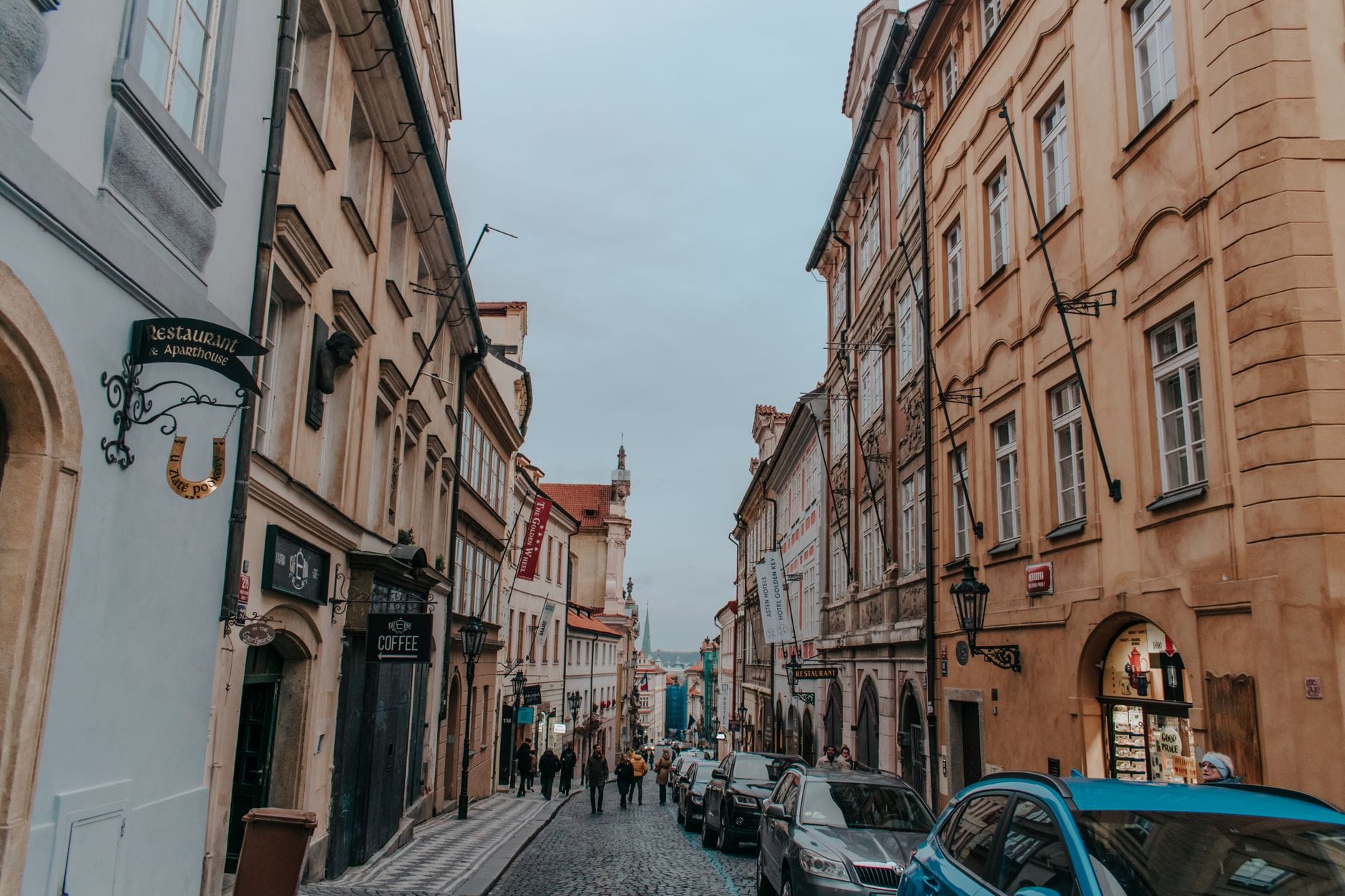 Eine Kopfsteinpflasterstraße, gesäumt von historischen Gebäuden und Fußgängern, typisch für Prags Wanderrouten, die die Notwendigkeit bequemer Schuhe verdeutlicht.