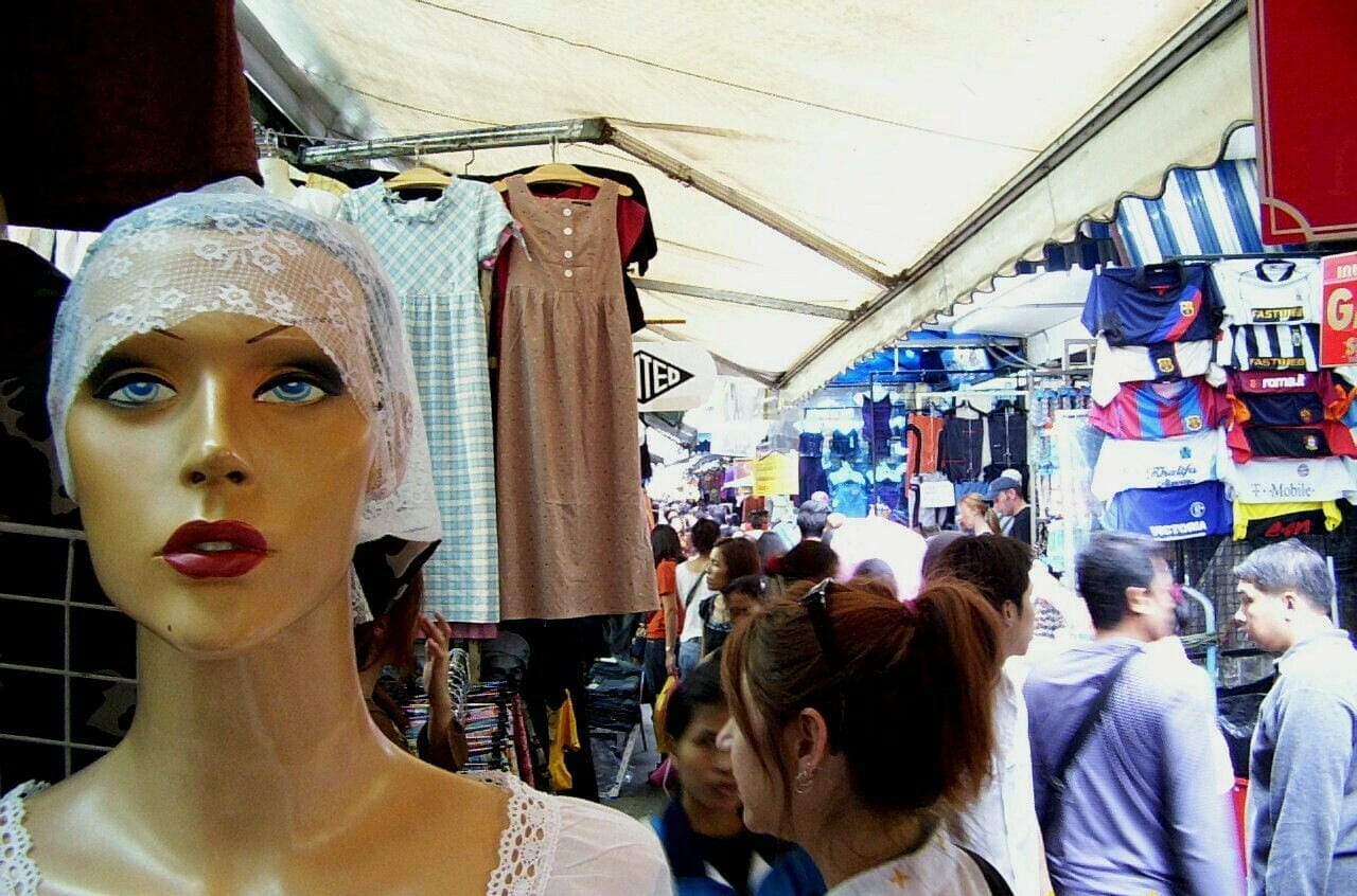 Bancarelle affollate di abbigliamento al Pratunam Market di Bangkok con capi di moda e acquirenti