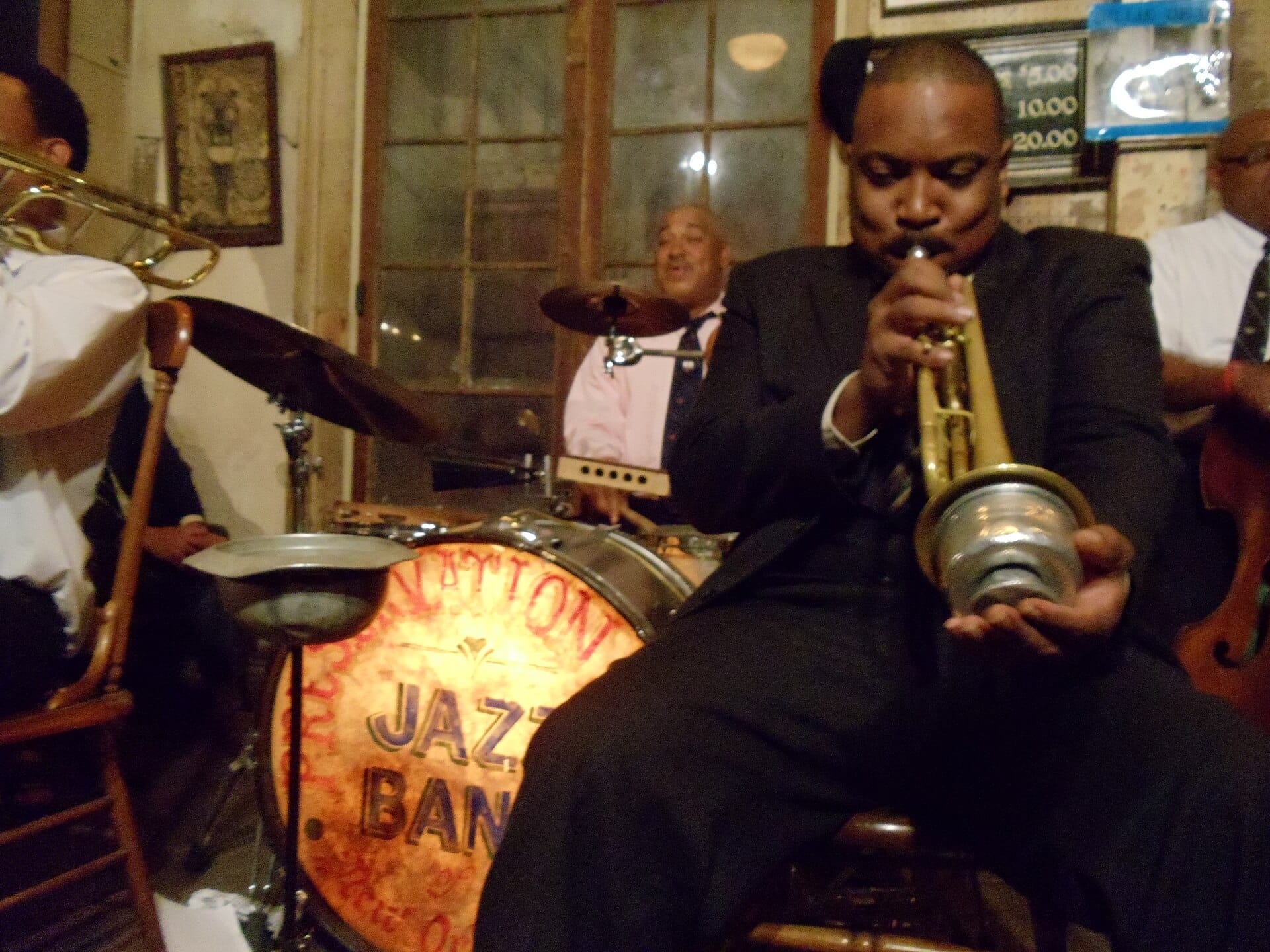 Musicisti jazz che si esibiscono dal vivo alla Preservation Hall, con Shannon Powell in primo piano e una batteria vintage in una sala accogliente e fiocamente illuminata.