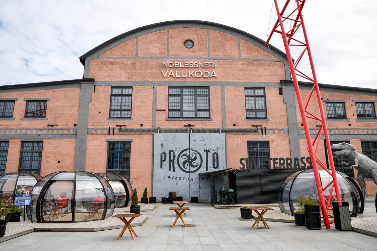 Frontfassade der PROTO Invention Factory in Tallinn mit Haupteingang, Logo und den Outdoor-Sitzdomkuppeln im Noblessner-Viertel.