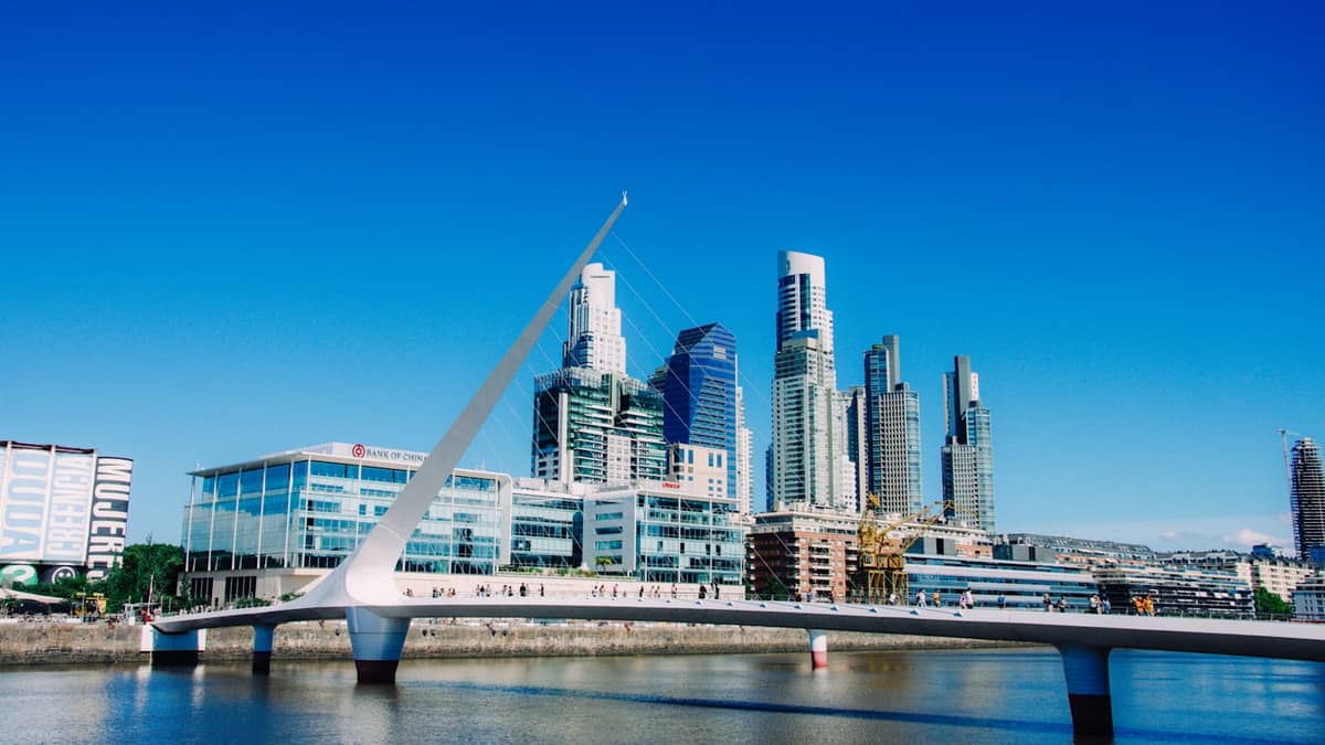 ตึกสูงสมัยใหม่และสะพาน Puente de la Mujer สะท้อนในสายน้ำที่ Puerto Madero ใต้ท้องฟ้าสีฟ้าสดใสที่บัวโนสไอเรส