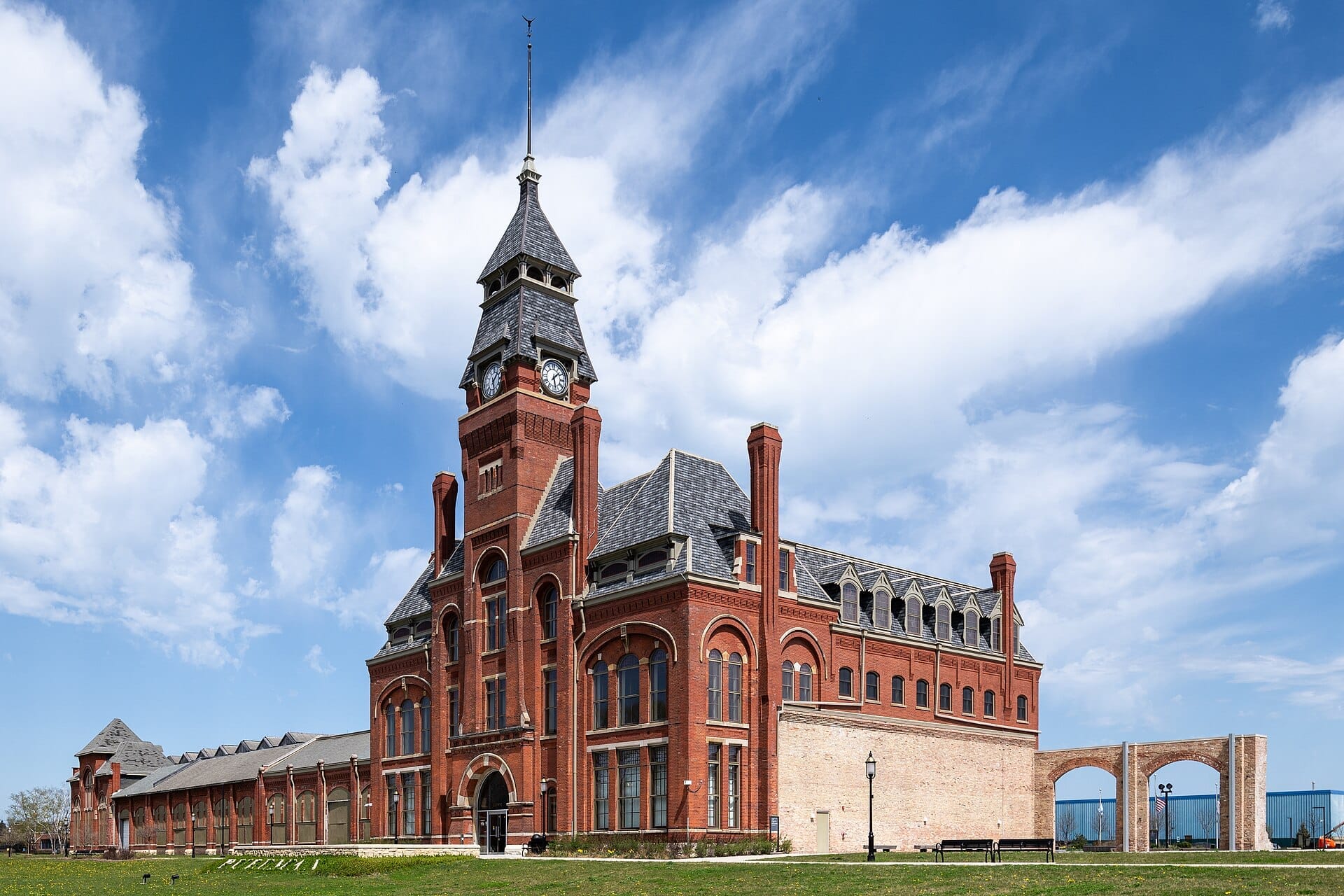 Storico edificio amministrativo in mattoni rossi al Pullman National Historical Park sotto un cielo azzurro brillante con nuvole sparse nel South Side di Chicago.