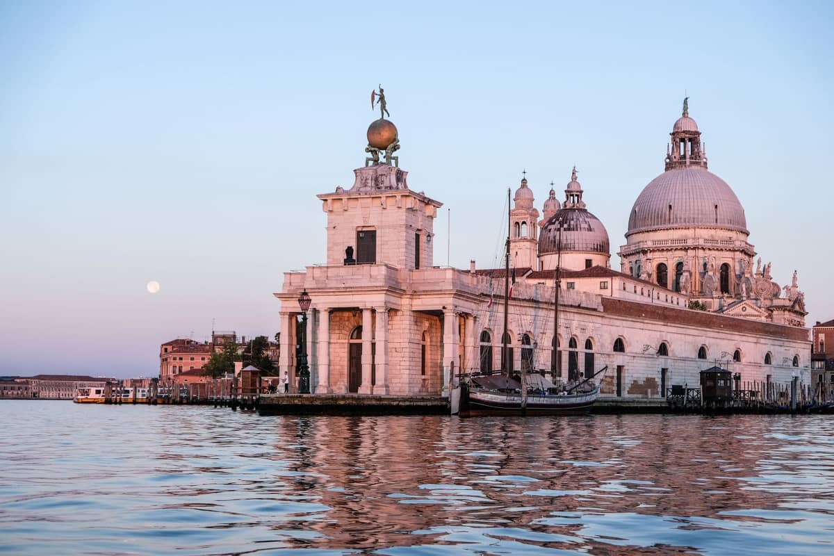 Punta della Dogana und die Kuppel der Santa Maria della Salute an der Spitze Dorsoduros in Venedig im Abendlicht, das sich im Wasser spiegelt.
