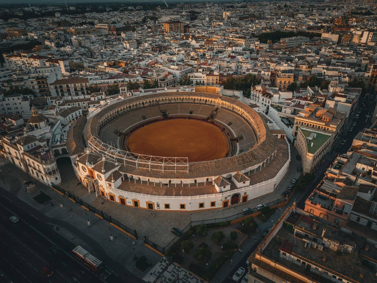 มุมสูงของสนามสู้วัว Real Maestranza de Caballería de Sevilla เห็นอาคารทรงกลมรายล้อมด้วยตึกเก่าในแสงพระอาทิตย์ตก
