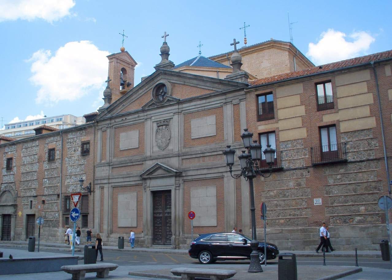 Facciata del Real Monasterio de las Descalzas Reales a Madrid, con esterno in mattoni, elaborate decorazioni in pietra e pedoni di passaggio.
