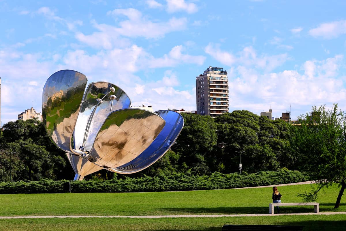 ประติมากรรมดอกไม้เหล็ก Floralis Genérica ท่ามกลางสวนเขียวในเรโคเลตา บัวโนสไอเรส มีอาคารเมืองเป็นฉากหลัง