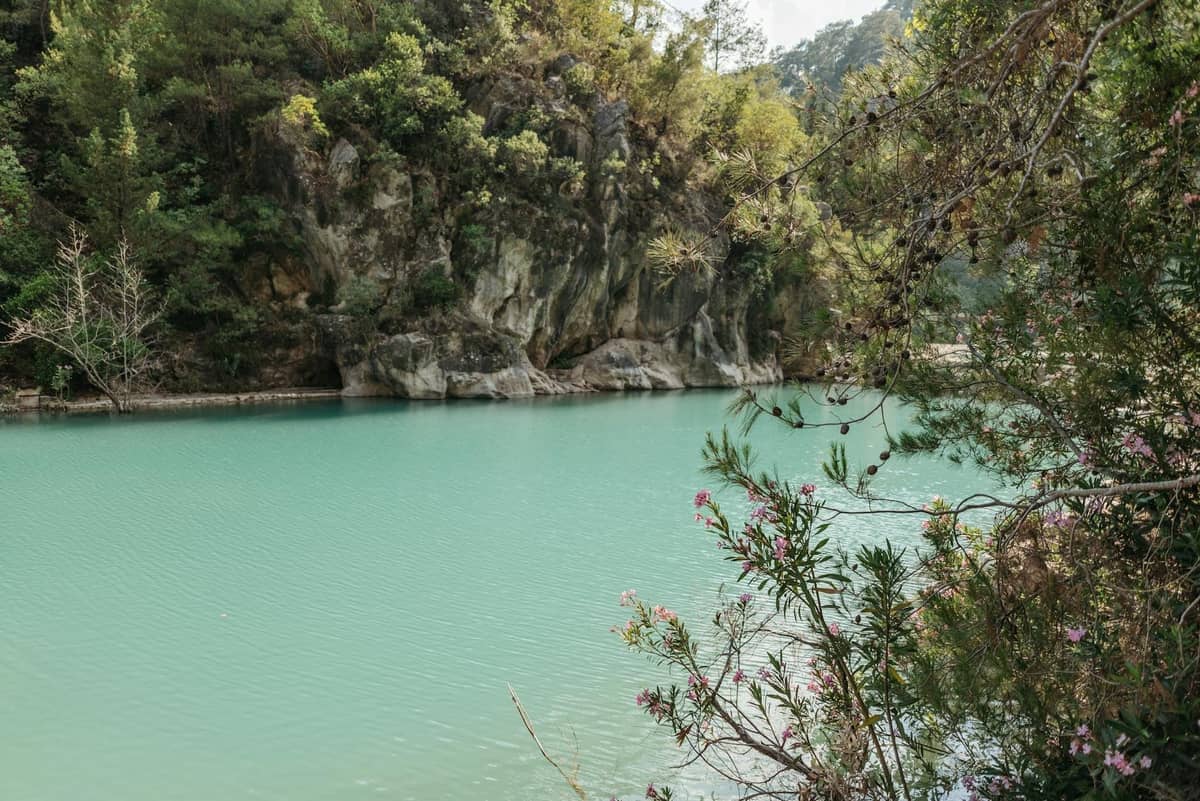 Turquoise artificial lake surrounded by rocky cliffs and trees, the landscape at Seven Springs in Rhodes.