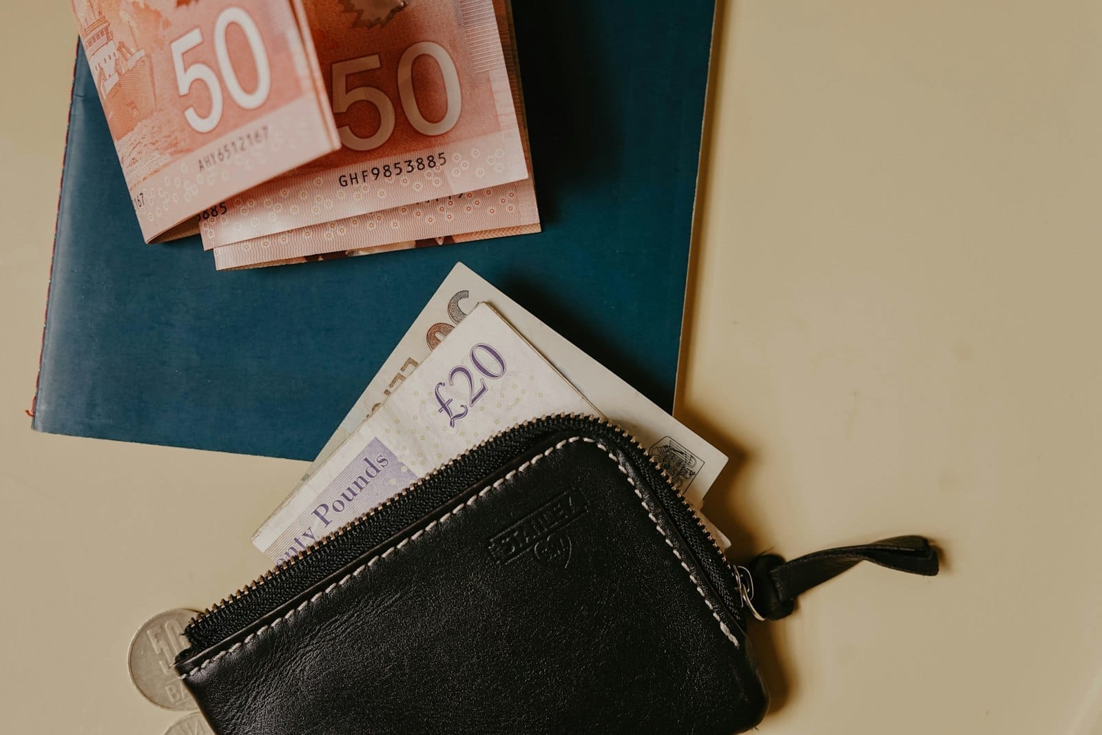 Carteira e diversas moedas, incluindo notas de Euro e libras esterlinas sobre uma mesa, sugerindo planejamento financeiro para viagens ao exterior.