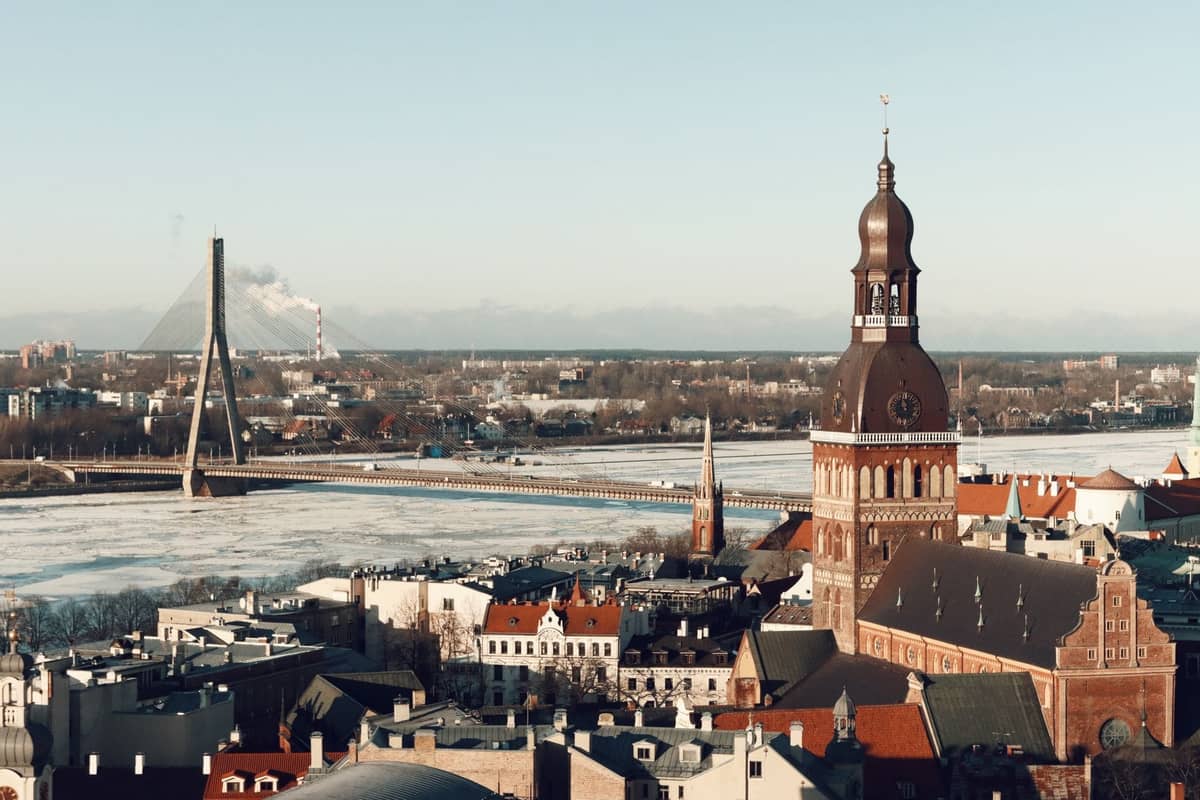 Panoramablick auf die Rigaer Altstadt und den Stadtkanal mit dem markanten Turm des Rigaer Doms und der modernen Brücke im Hintergrund.