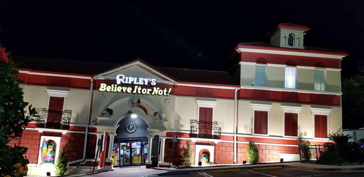 Haupteingang von Ripley's Believe It or Not! Orlando bei Nacht, mit dem markanten rot-weißen schiefen Gebäude und dem großen Eingangsschild.