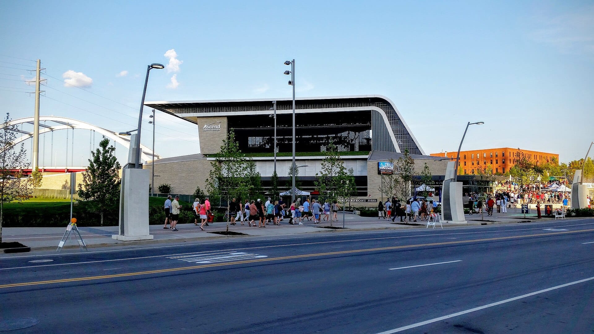 Vista del Ascend Amphitheater en Riverfront Park en Nashville, con multitudes reunidas en el exterior y el icónico puente al fondo.