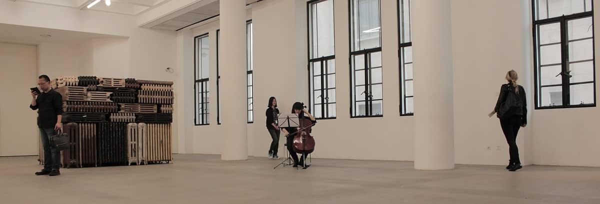 Helles, weitläufiges Inneres des Rockbund Art Museums mit Besuchern, großen Fenstern und einer zeitgenössischen Kunstinstallation aus gestapelten Heizkörpern – modern und luftig.