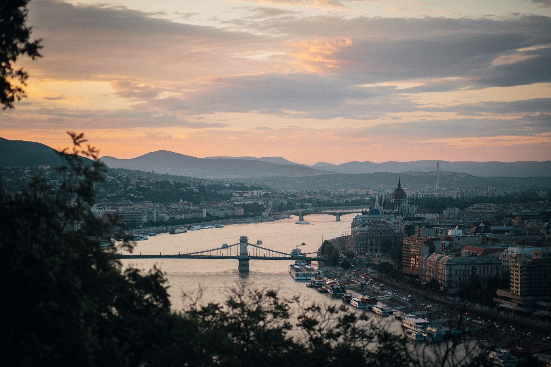 Skyline von Budapest bei Sonnenuntergang mit Donau, Chain Bridge und Parlament mit Hügeln im Hintergrund