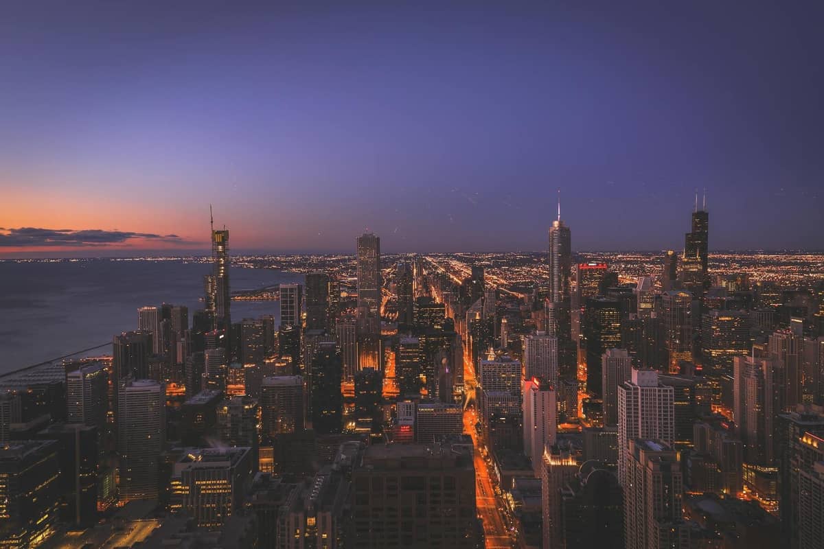 Horizonte de Chicago al atardecer con edificios iluminados y el lago Míchigan, mostrando los icónicos rascacielos de la ciudad y una romántica atmósfera de crepúsculo.