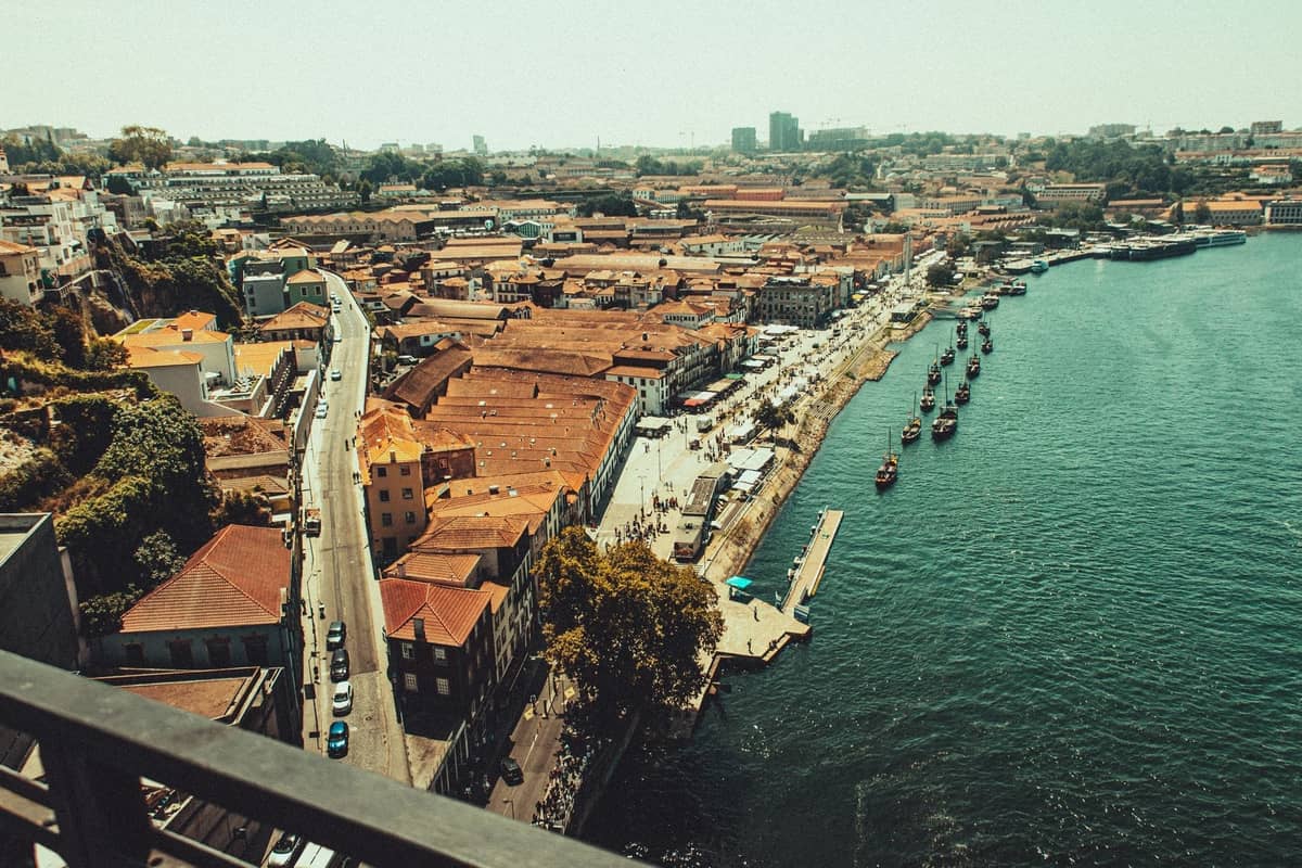 Vista aérea de Vila Nova de Gaia con hileras de bodegas de vino de Oporto y el río Douro, barcos tradicionales amarrados a lo largo del paseo marítimo.