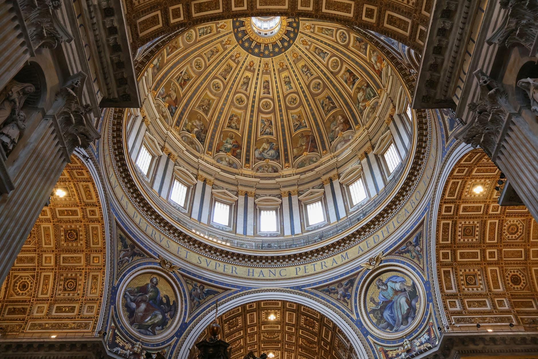 Wide interior view of St. Peter’s Basilica dome and ornate architecture, with gold accents and religious artwork clearly visible.