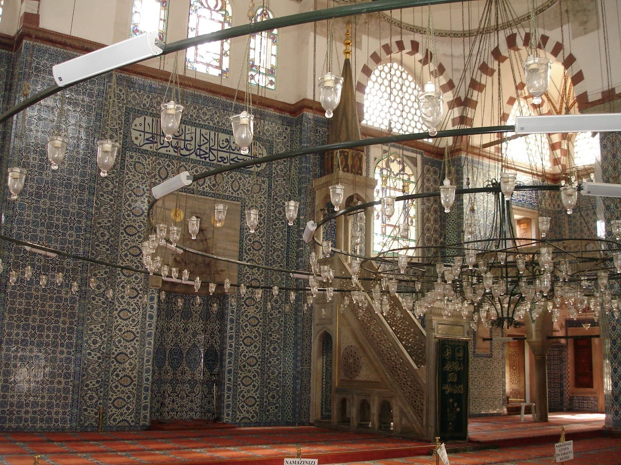 L'interno della Moschea di Rüstem Paşa presenta pareti ricoperte di intricati piastrelle di Iznik blu, finestre ad arco con vetrate colorate e un grande lampadario centrale.
