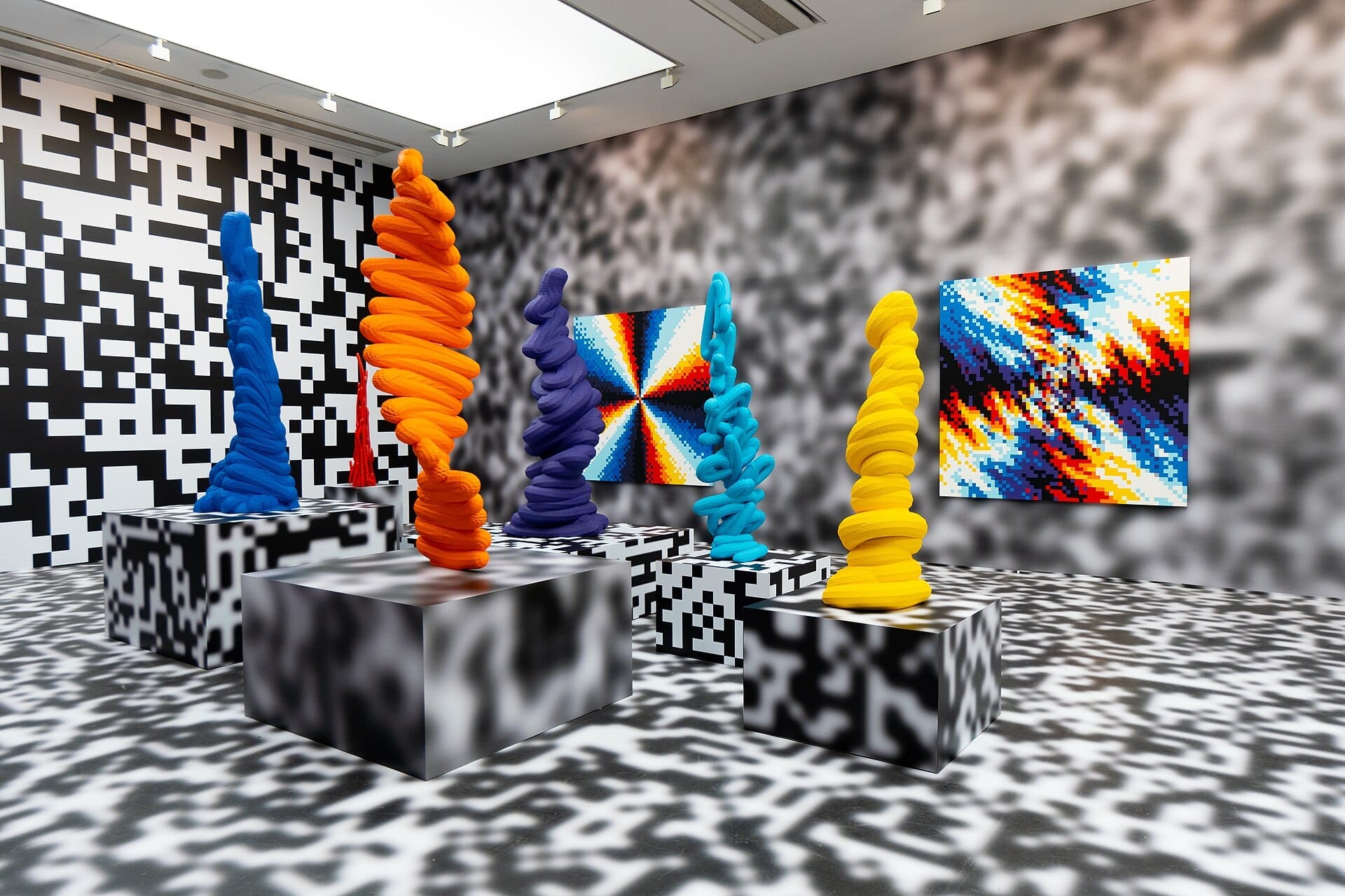 Sculture astratte colorate e dipinti pixelati esposti in una sala moderna e luminosa della Saatchi Gallery, Chelsea, Londra.