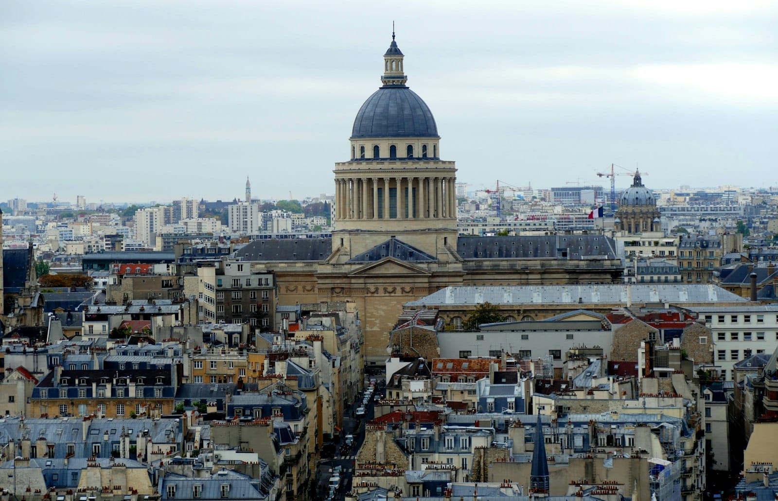Vista panoramica del Panthéon nel Quartiere Latino, con i classici tetti parigini e il profilo della città che si estende verso l'orizzonte sotto un cielo nuvoloso.