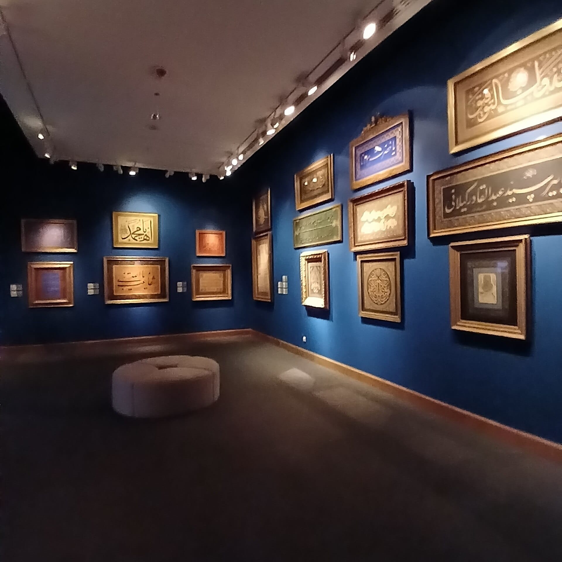 Opere di calligrafia ottomana incorniciate esposte su pareti blu intenso in una galleria debolmente illuminata del Sakıp Sabancı Müzesi a Istanbul.