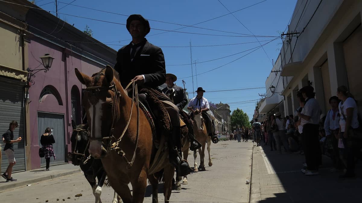 ขบวนกาวโช่บนหลังม้าผ่านถนนหลักของเมือง San Antonio de Areco โดยมีผู้คนทั้งสองฝั่งยืนดูบนถนนสายโคโลเนียล