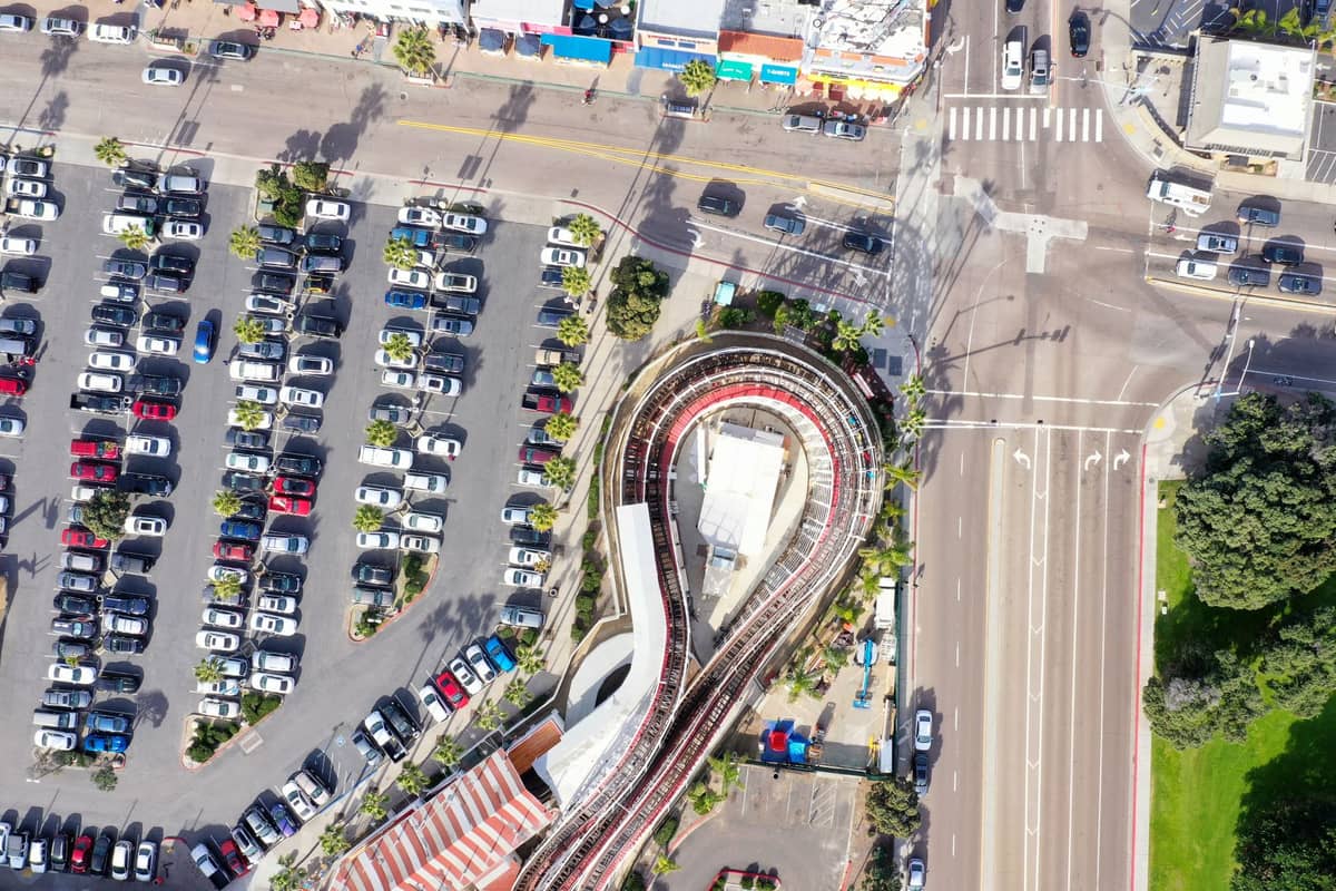 มุมมองทางอากาศของ Belmont Park พร้อมรถไฟเหาะไม้อันเป็นสัญลักษณ์ ที่จอดรถ และถนนใกล้เคียงใน San Diego
