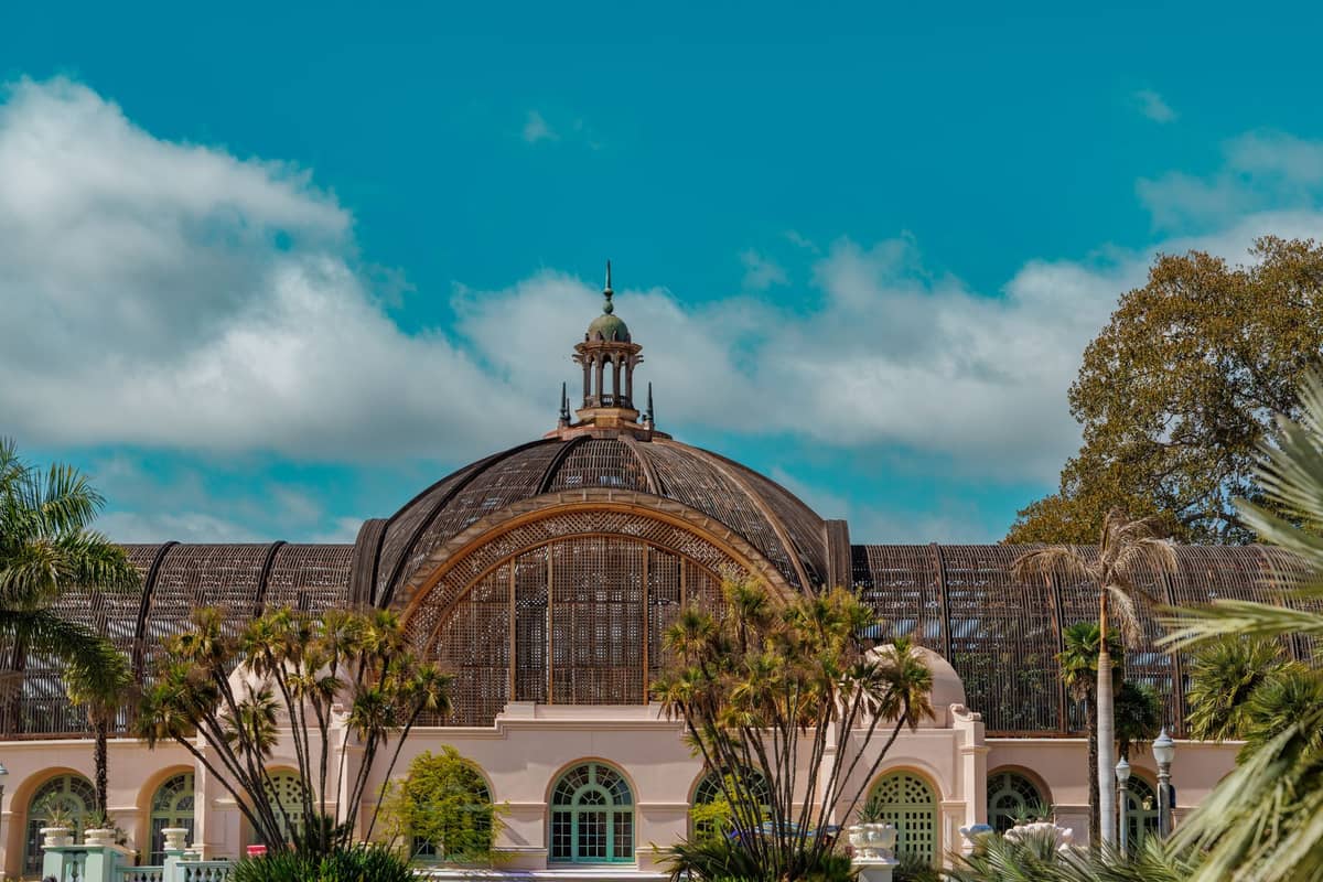 Das ikonische Balboa Park Botanical Building in San Diego an einem sonnigen Tag, eingerahmt von Palmen und blauem Himmel.