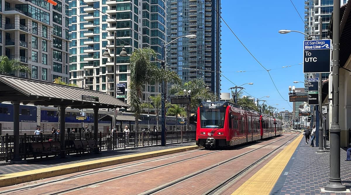รถราง San Diego Trolley ที่สถานี Santa Fe Depot พร้อมอาคารสูงใจกลางเมืองและต้นปาล์มในวันที่แดดจ้า