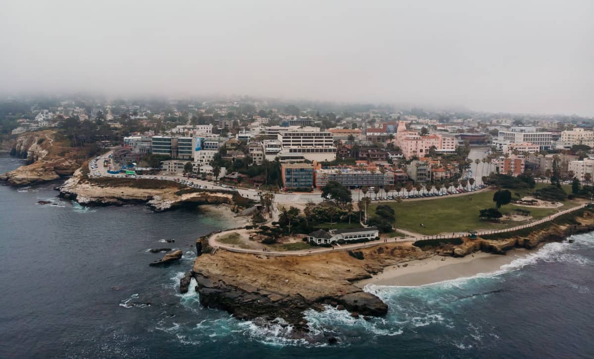 Luftaufnahme der Küste von La Jolla mit Hotels, Parks und Straßen in der Nähe des Ozeans unter einem nebligen Himmel.
