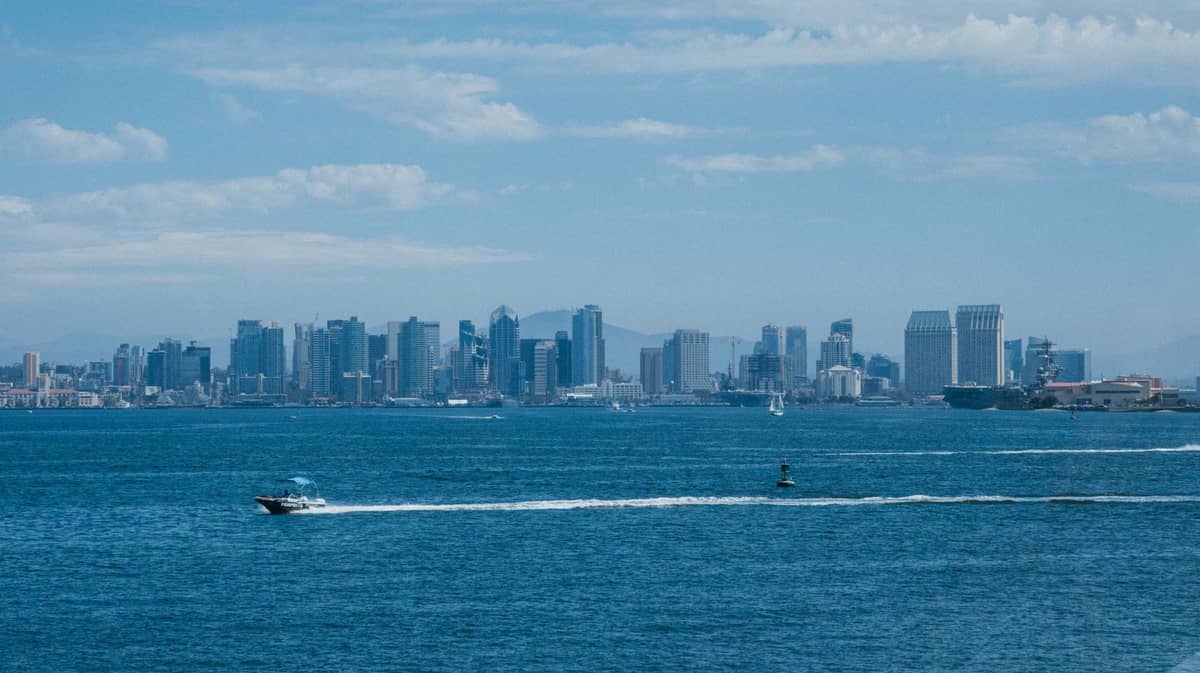 Weite Aussicht auf die Skyline von San Diego von der anderen Seite der Bucht mit Booten und klarem blauen Himmel über der Stadt.