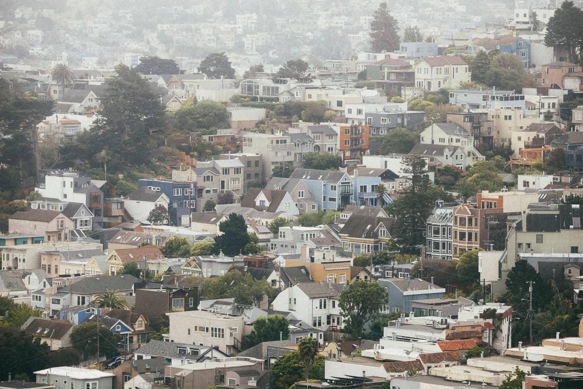 Weite Landschaftsansicht der Wohnviertel von San Francisco mit dichten Reihen von Häusern aus der Mitte des Jahrhunderts und Stuckhäusern unter bewölktem Himmel.