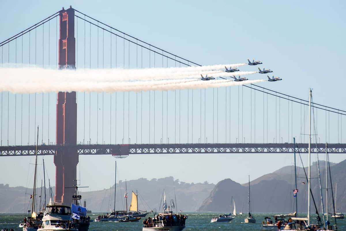 Jets de los Blue Angels de la Marina de EE. UU. volando en formación sobre el Golden Gate Bridge con barcos en la Bahía de San Francisco durante la Fleet Week.