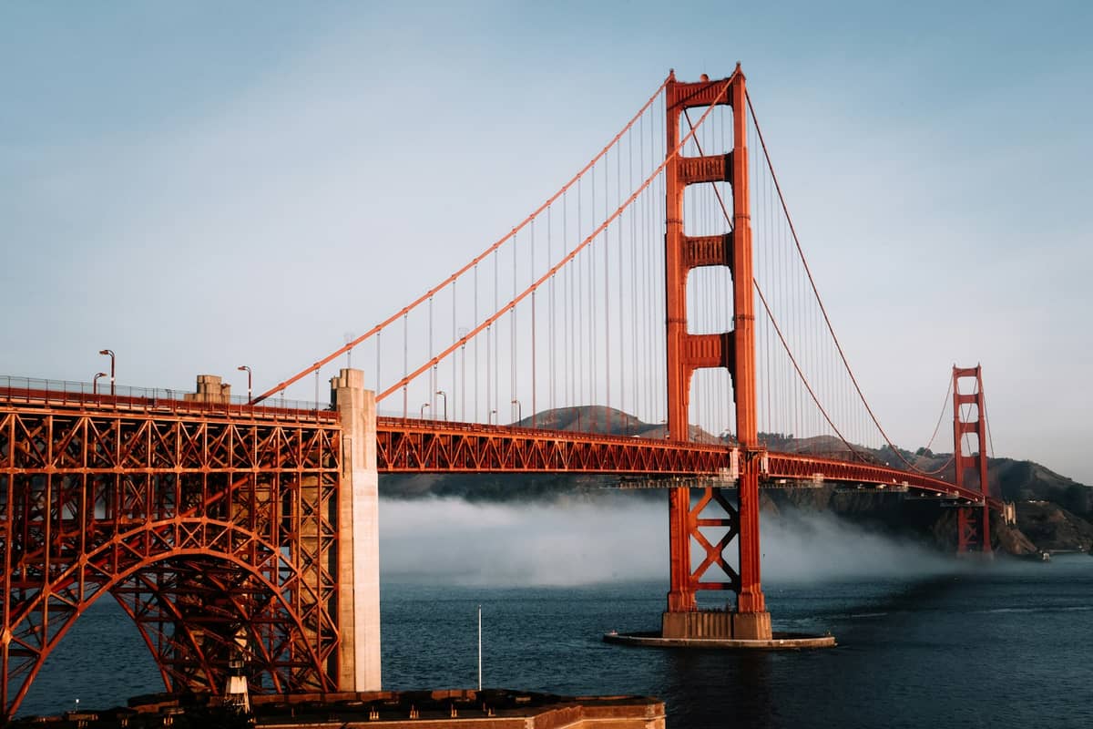 El puente Golden Gate con la característica niebla veraniega deslizándose bajo la estructura, fotografiado en formato horizontal durante el día en San Francisco.