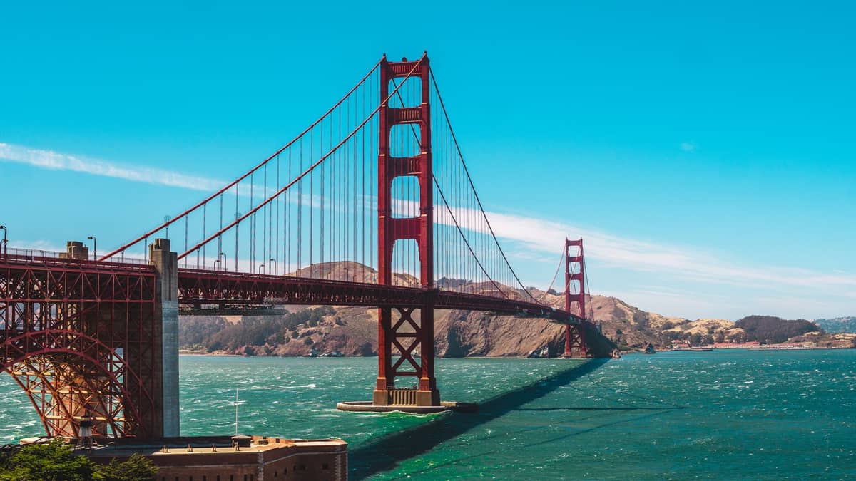 El puente Golden Gate cruzando la bahía con colinas al fondo en un día soleado en San Francisco.