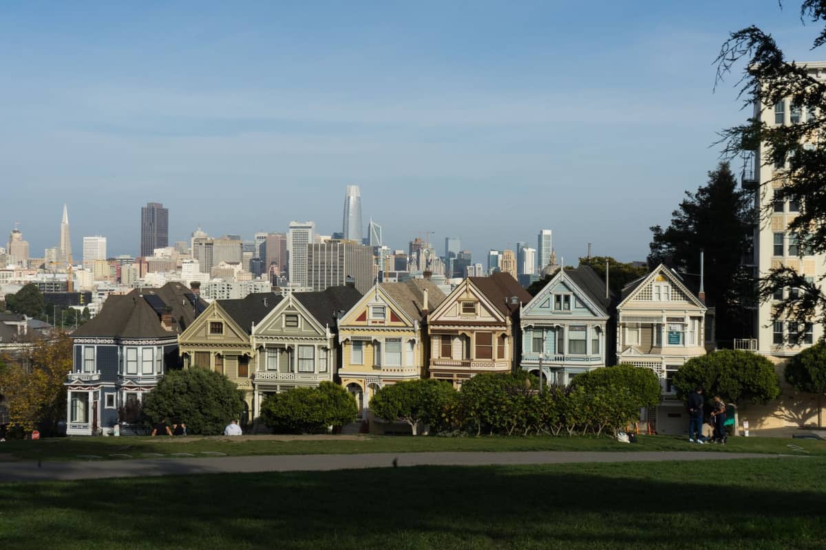 Die Painted Ladies, viktorianische Häuser mit der Skyline von San Francisco im Hintergrund an einem klaren Tag, gesehen vom Alamo Square Park.