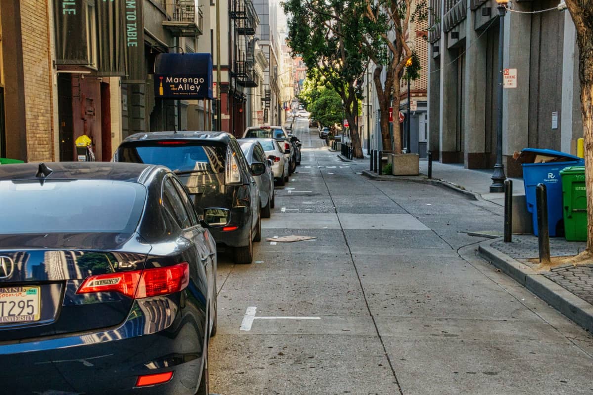 Miejska boczna ulica w San Francisco z zaparkowanymi samochodami, alejką i budynkami mieszkalnymi w ciągu dnia.