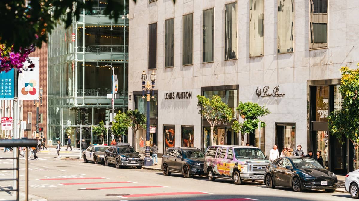 Esterno di Louis Vuitton e altri negozi di lusso lungo una strada animata nel quartiere commerciale di Union Square a San Francisco.