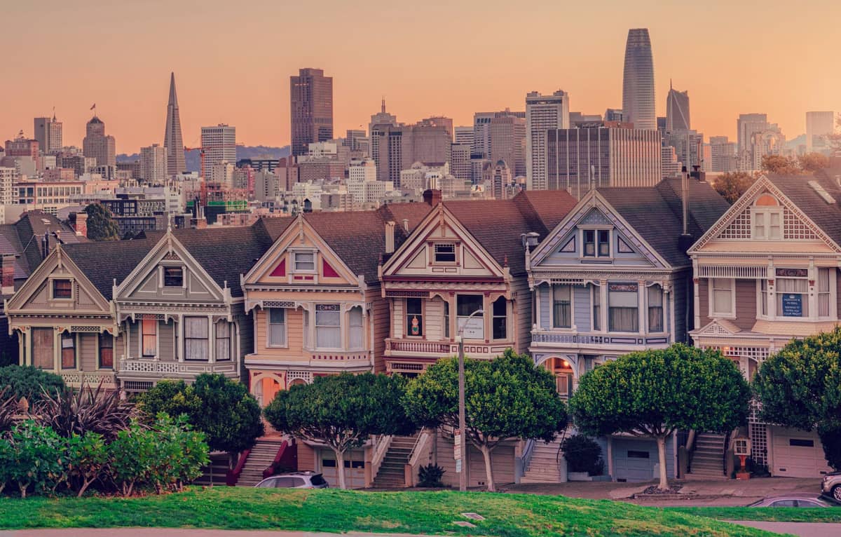 Las icónicas casas victorianas Painted Ladies en Alamo Square con el horizonte de San Francisco detrás al atardecer.